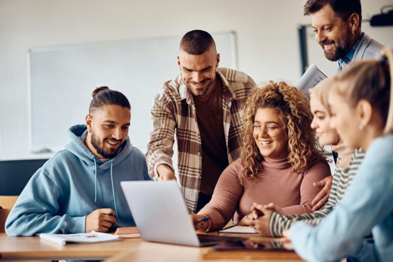 happy college students and their teacher using computer-in-the classroom